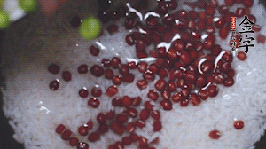將炒好的食材和大米、紅豆一起放進(jìn)電飯鍋煮。