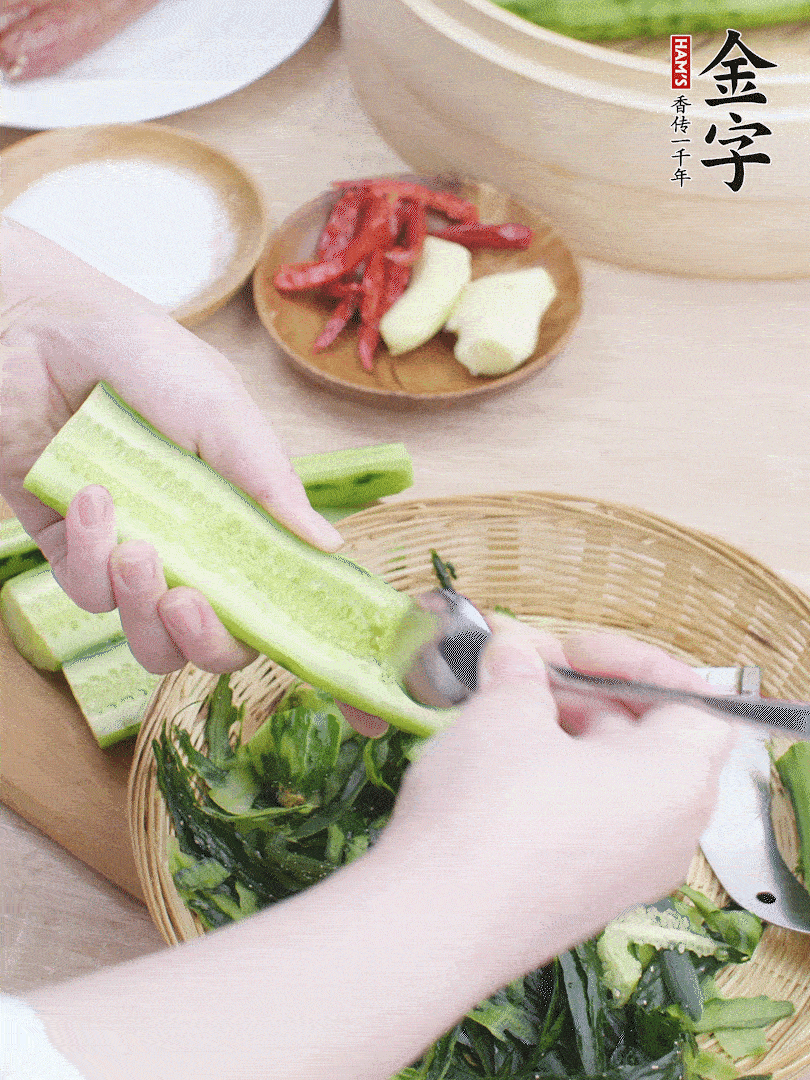 黃瓜削皮，對半切開，勺子挖去內(nèi)瓤，斜刀切片。青蒜斜刀切段。