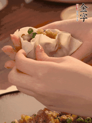 取一大勺餡料放進(jìn)餃子皮里，用大拇指按住頂部餡料，再用虎口掐出形狀。